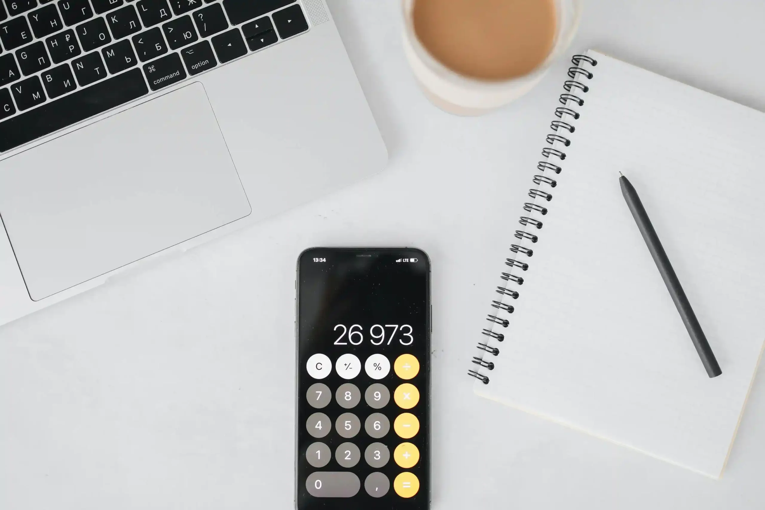 Smartphone affichant une calculatrice à côté d’un ordinateur portable pour illustrer le coût réel d’un site web créé avec l’intelligence artificielle.