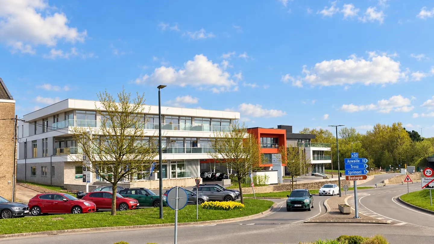 Entrée du centre de Beaufays et ses bâtiments professionnels sous un ciel ensoleillé